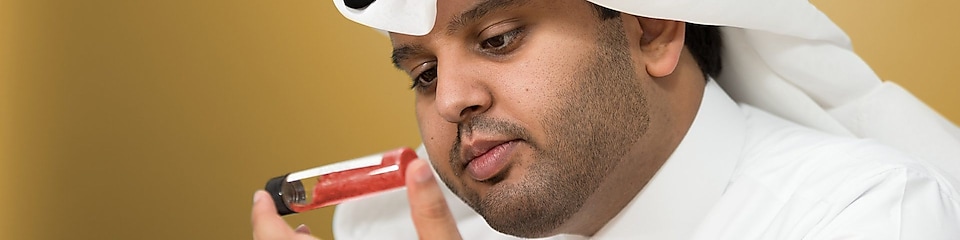 Мохаммед Аль Атаба проверяет содержимое закрытой пробкой лабораторной пробирки